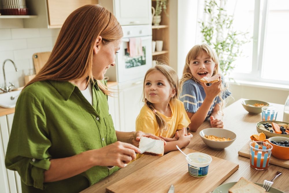 Eine Frau sitzt mit zwei Kindern beim Frühstückstisch